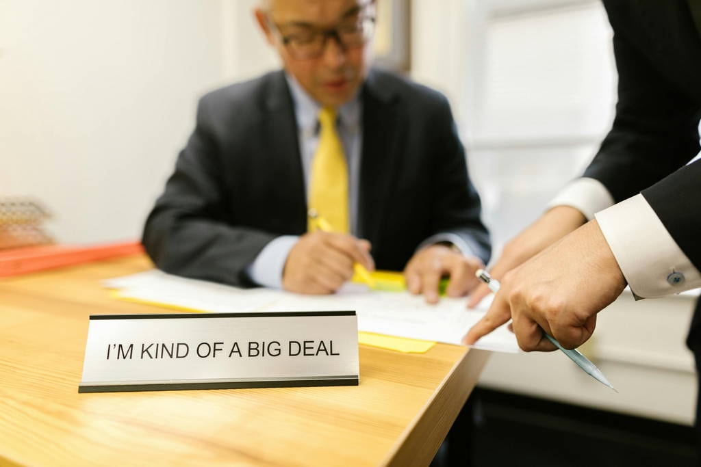 Businessman at desk with humorous nameplate, representing misconceptions about leadership titles versus reflective leadership. Reflection for Leaders