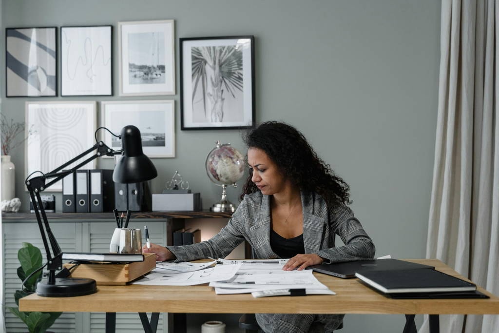 Focused businesswoman reviewing documents at a clean, organized desk to support strategic thinking. Reduce Cognitive Load to Avoid Leadership Blind Spots.