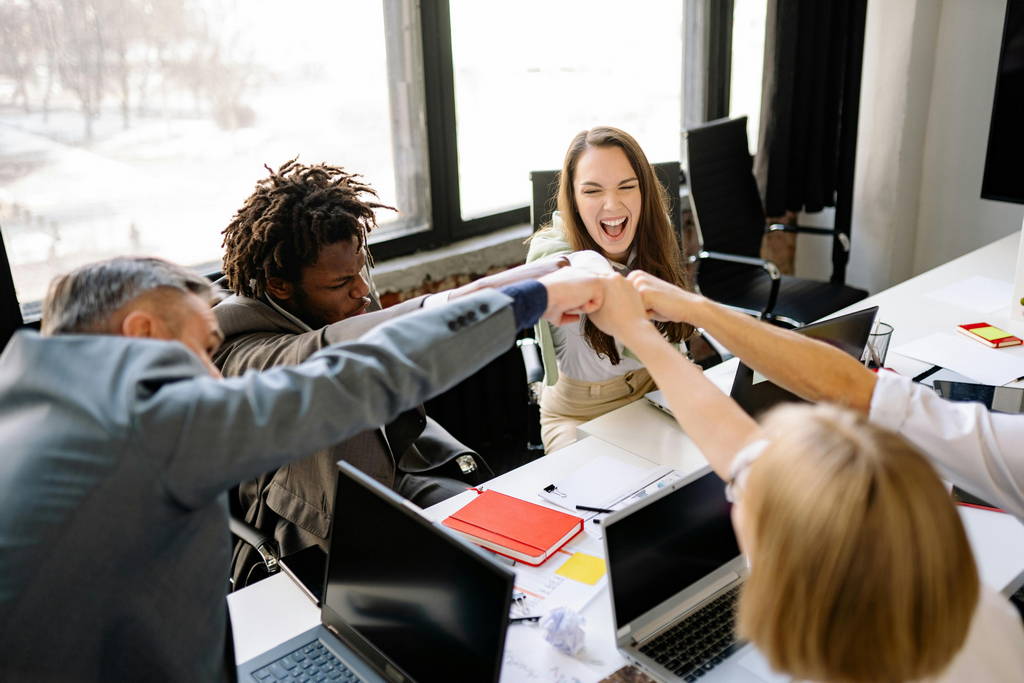 A motivated business team celebrating success with a fist bump, demonstrating strong leadership skills and teamwork.