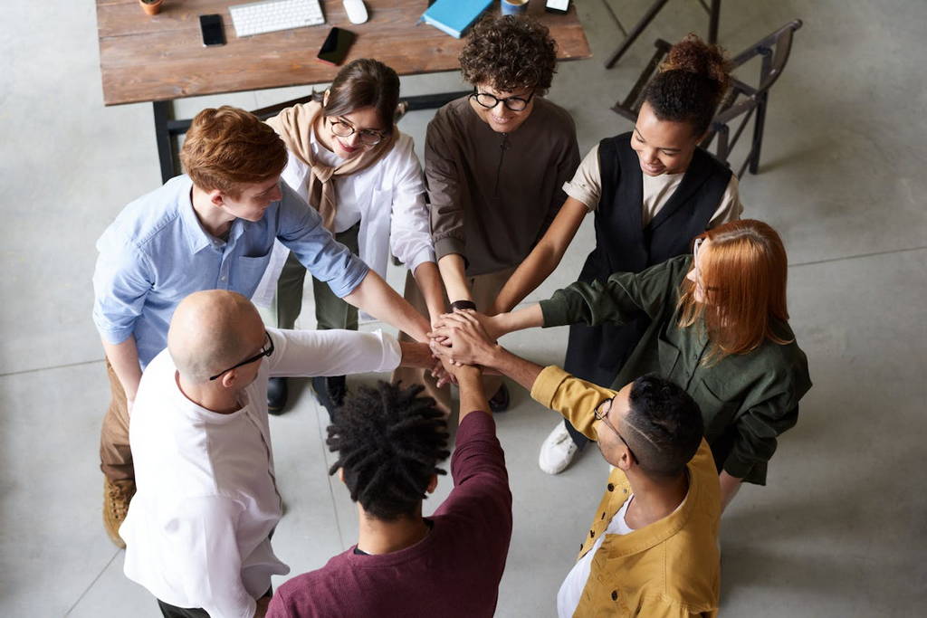 A diverse business team joining hands in a display of trust, collaboration, and emotionally intelligent leadership.