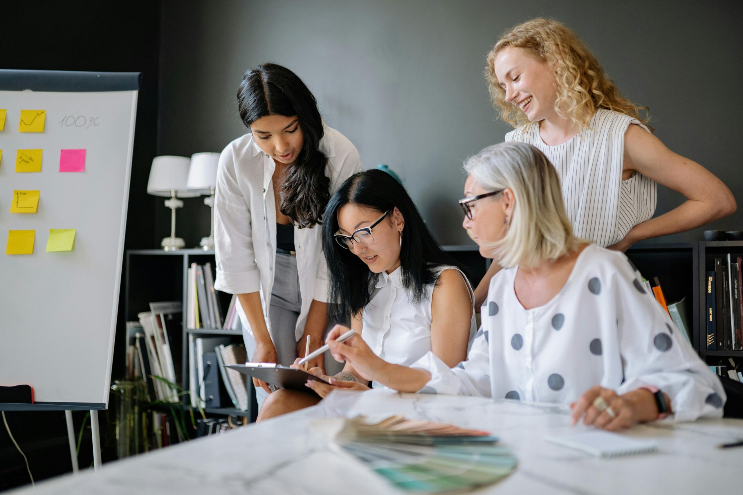 Group of professional women collaborating at a computer, promoting learning and contributor safety in the workplace.