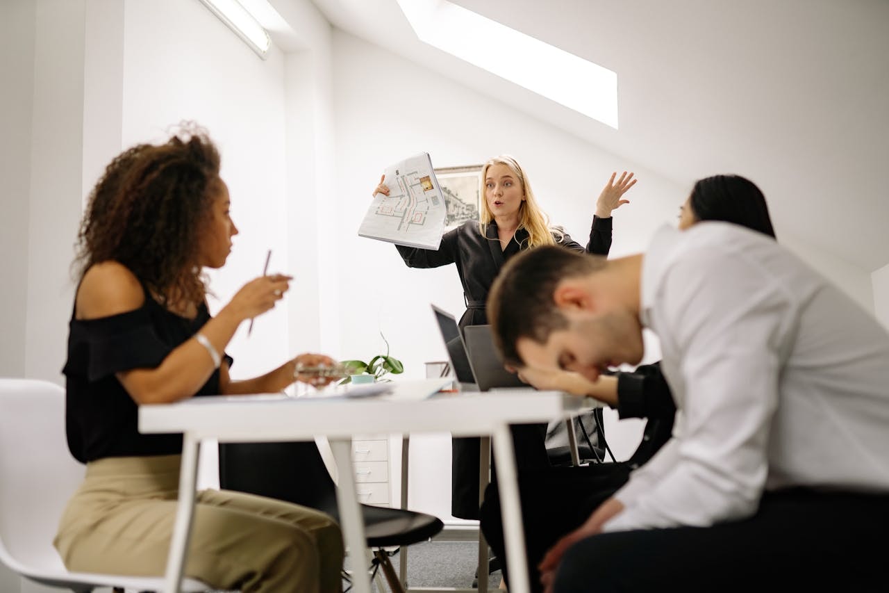 Frustrated team in a tense meeting, illustrating the challenges of low psychological safety in the workplace.